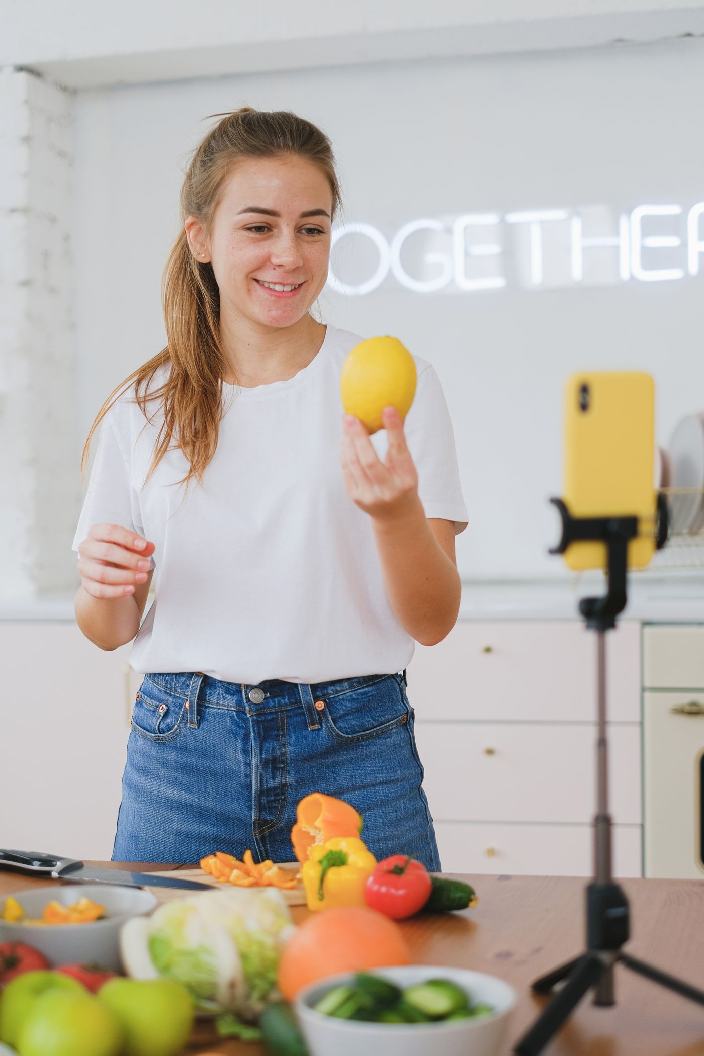 A woman recording a food video in a bright kitchen.