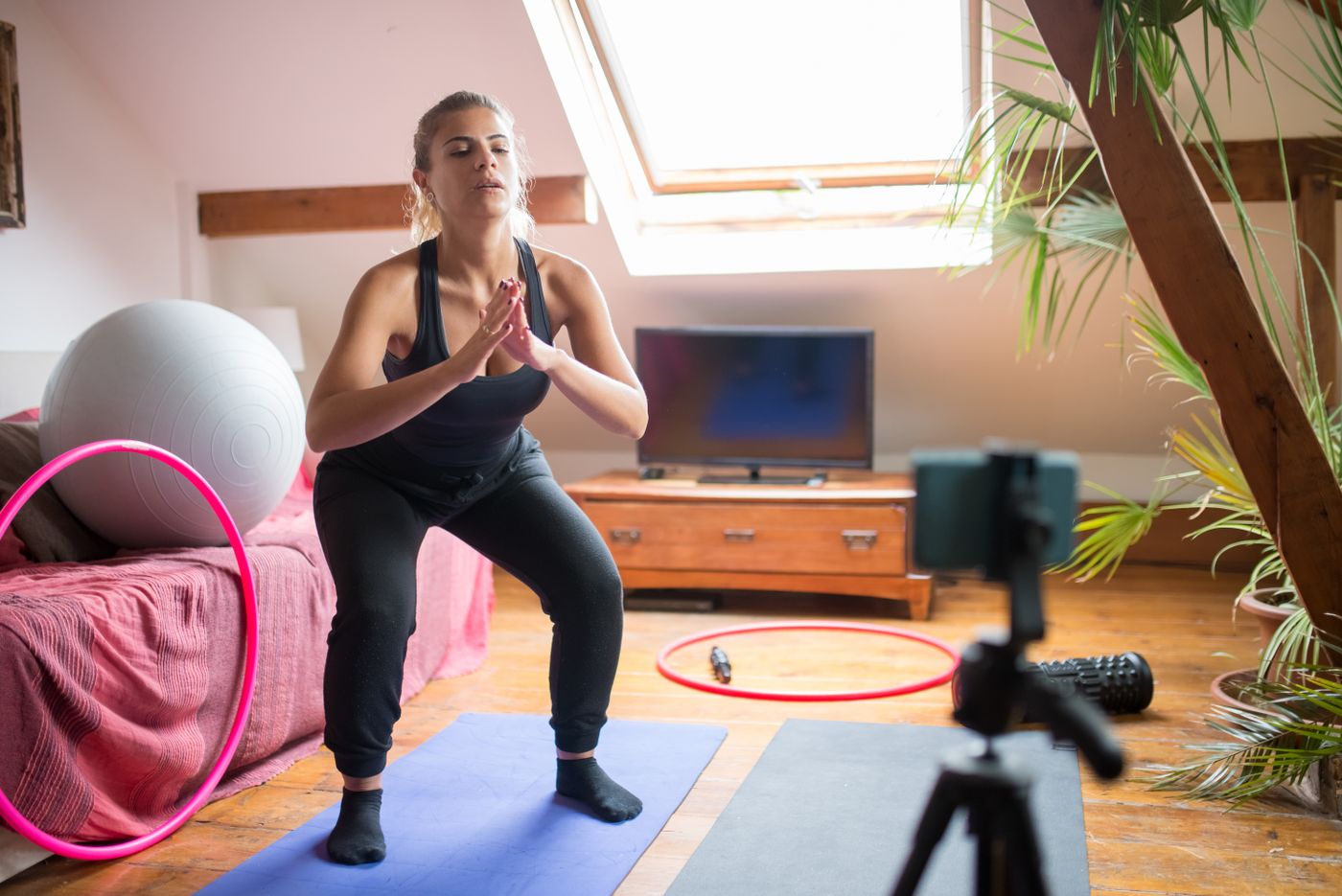 A woman exercising on a mat while recording herself at home.